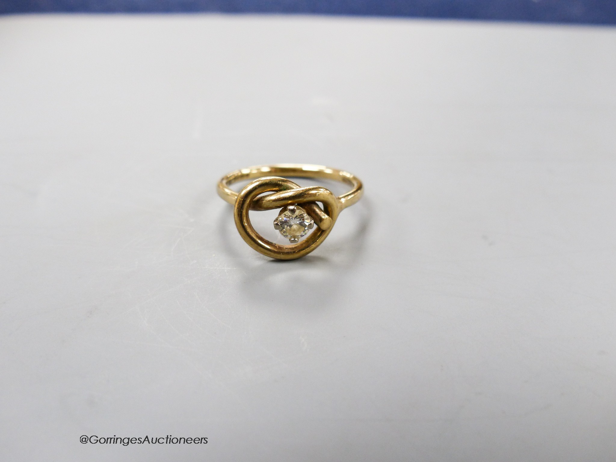 A 9ct gold and single stone diamond set 'knot' ring, size P, gross 3.3 grams.